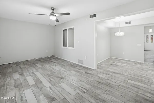 a view of empty room with wooden floor and fan