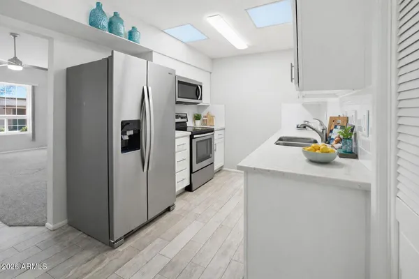 a kitchen with stainless steel appliances a white refrigerator a stove a sink a washer and dryer with wooden floor