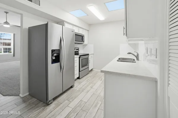 a kitchen with stainless steel appliances a refrigerator a sink and wooden floor