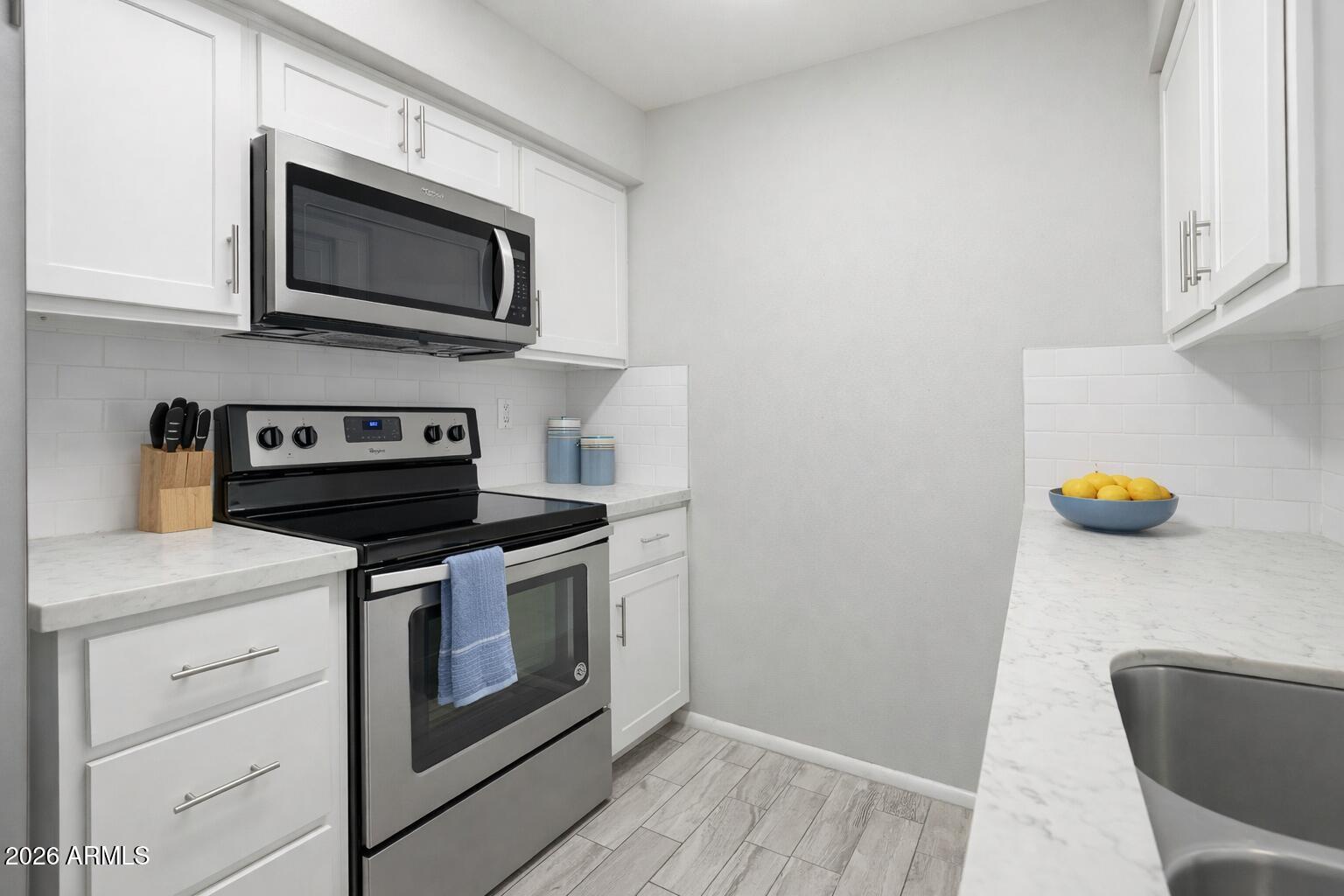 10030 West Royal Oak Road, Unit L Sun City, AZ 85351 - Photo 6 of 30 a kitchen with a stove and a microwave