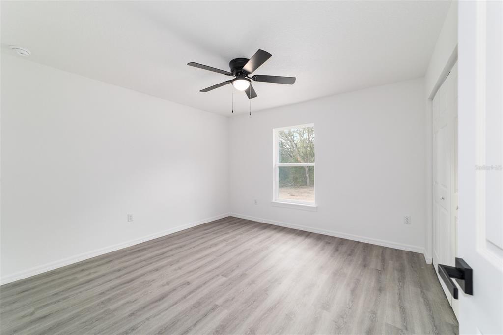 1922 Southwest Little Cliffs Drive Dunnellon, FL 34431 - Photo 25 of 37 an empty room with wooden floor fan and windows