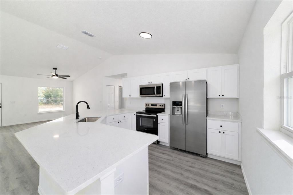 1922 Southwest Little Cliffs Drive Dunnellon, FL 34431 - Photo 6 of 37 a kitchen with stainless steel appliances a refrigerator sink and white cabinets