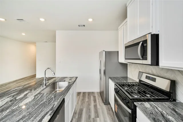 a kitchen with granite countertop a sink stove and microwave