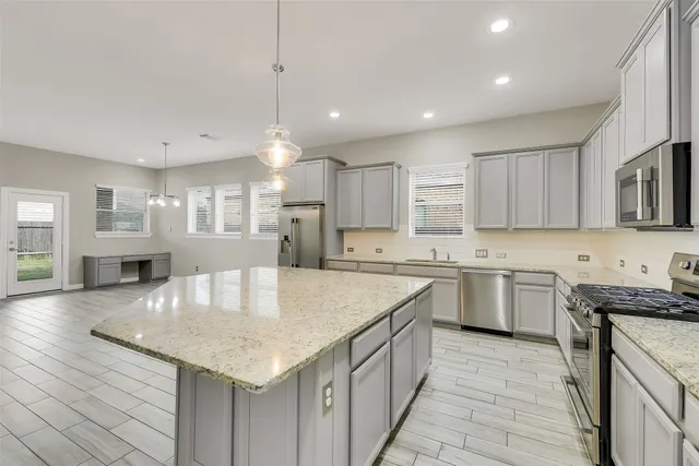 a kitchen with stainless steel appliances granite countertop a kitchen island a stove a sink a microwave a dining table and chairs