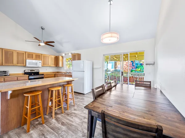 a kitchen with stainless steel appliances granite countertop a stove top oven a refrigerator a sink dishwasher a dining table and chairs with wooden floor