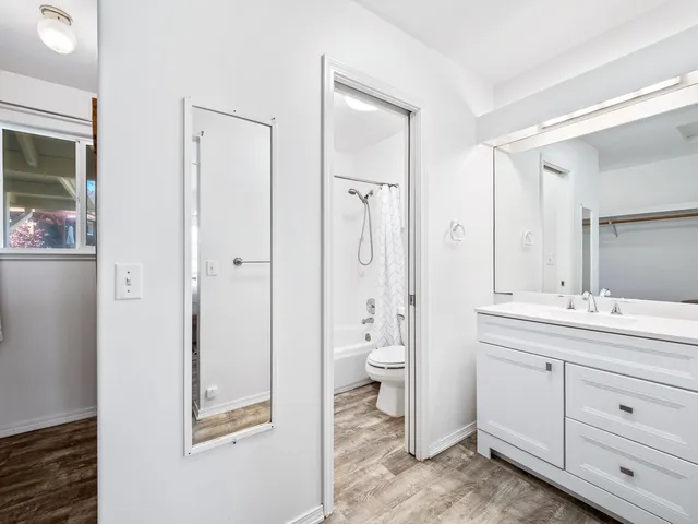 a spacious bathroom with a granite countertop toilet a sink and a mirror