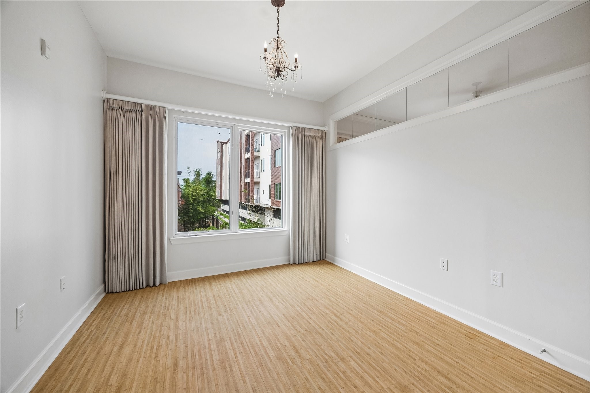 100 Willard Street, Unit 15 Houston, TX 77006 - Photo 18 of 25 Secondary bedroom with laminate flooring, high ceilings, large window, and designer lighting – ideal for guests, roommates, or a home office setup.