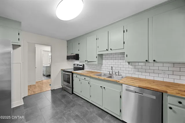 a kitchen with stainless steel appliances granite countertop a sink a stove and a refrigerator