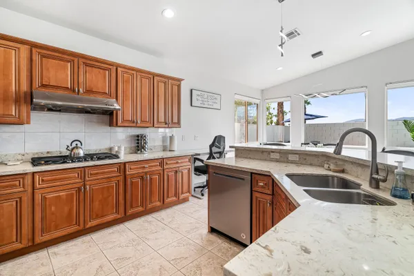a kitchen with stainless steel appliances granite countertop a sink dishwasher stove refrigerator and cabinets