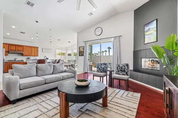 a living room with furniture kitchen view and a wooden floor