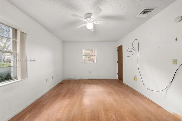 an empty room with windows and ceiling fan