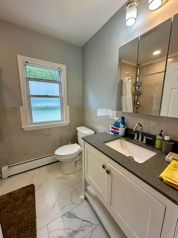 a bathroom with a granite countertop sink toilet and a mirror