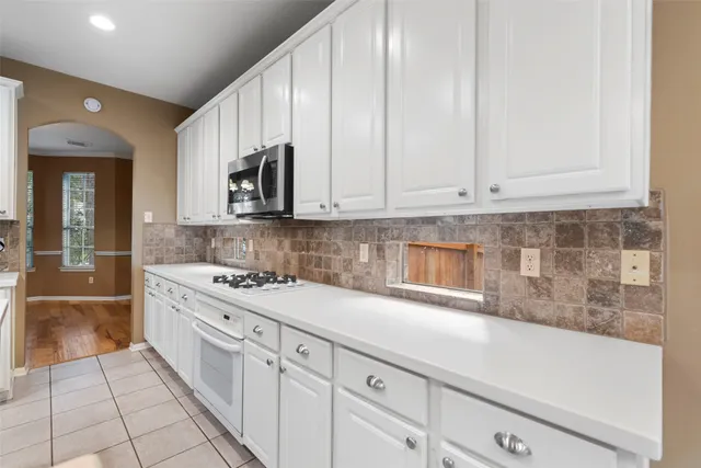 a kitchen with white cabinets and window