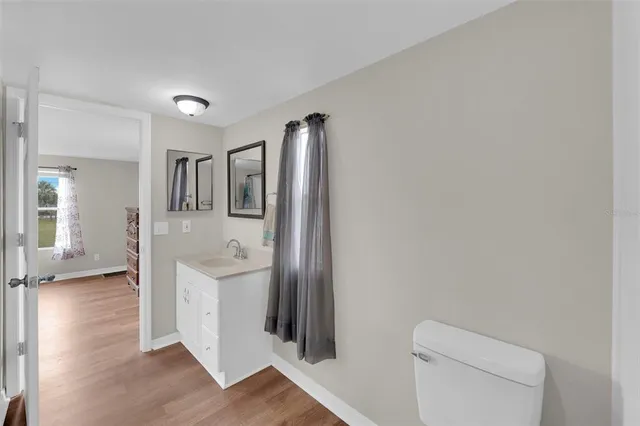 a view of a room with wooden floor a ceiling fan and windows