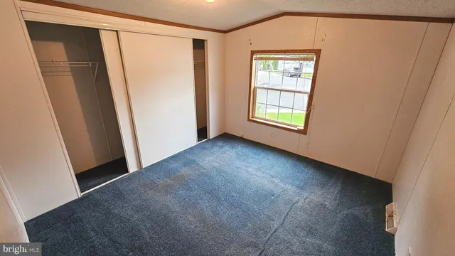 a view of an empty room with window and closet area