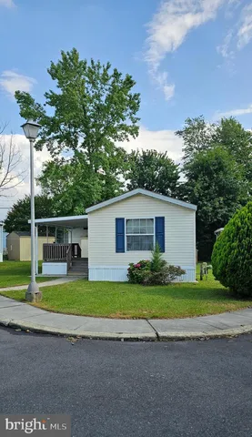 a white house with a small yard and big trees with a big yard