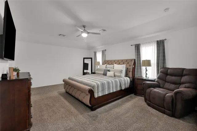 a spacious bedroom with a bed a flat screen tv and a couch