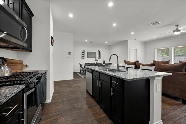 a kitchen with granite countertop a sink stove top oven and cabinets