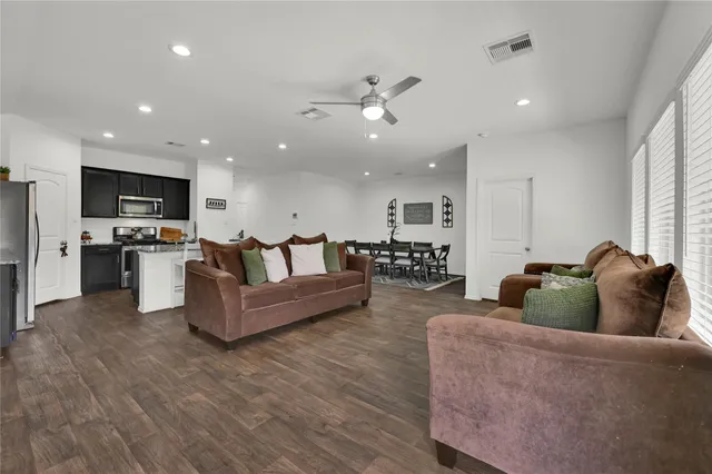 a living room with furniture kitchen view and a chandelier