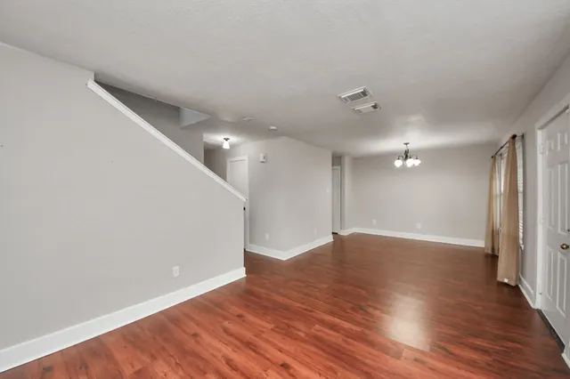 a view of a hallway with wooden floor and chandelier