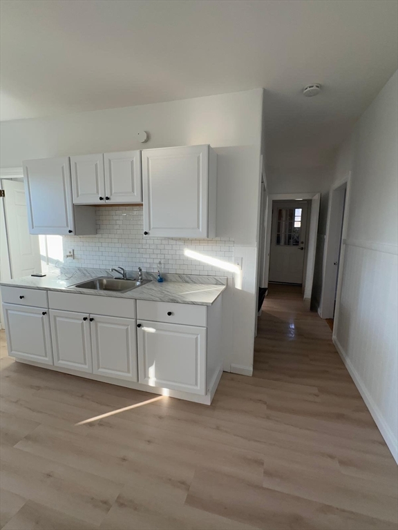 11 Alpine Street, Unit 3 Worcester, MA 01610 - Photo 3 of 14 a kitchen with granite countertop a stove a sink and white cabinets with wooden floor