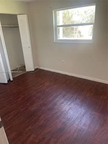 an empty room with wooden floor and window