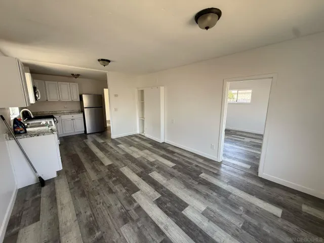 a view of a hallway to a room with wooden floor and windows