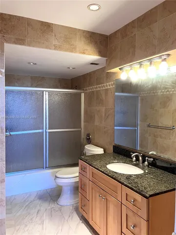 a bathroom with a granite countertop sink a toilet and a shower