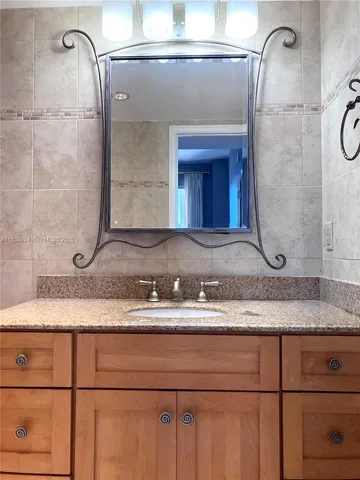 a bathroom with a granite countertop sink and a mirror