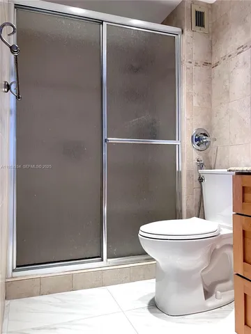 a white toilet sitting next to a shower