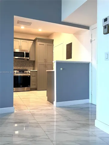 a view of kitchen with stainless steel appliances wooden floor and living room