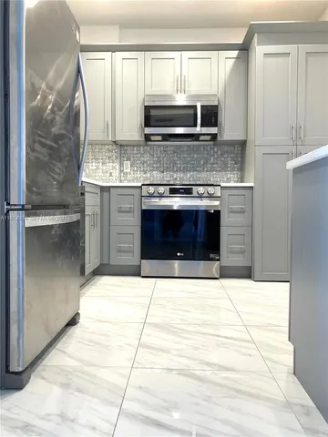 a kitchen with stainless steel appliances kitchen island granite countertop a stove a sink and a microwave