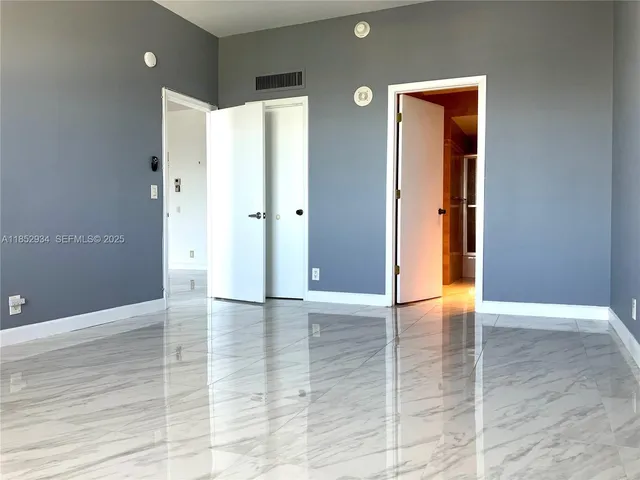 a view of an empty room with wooden floor and a bathroom