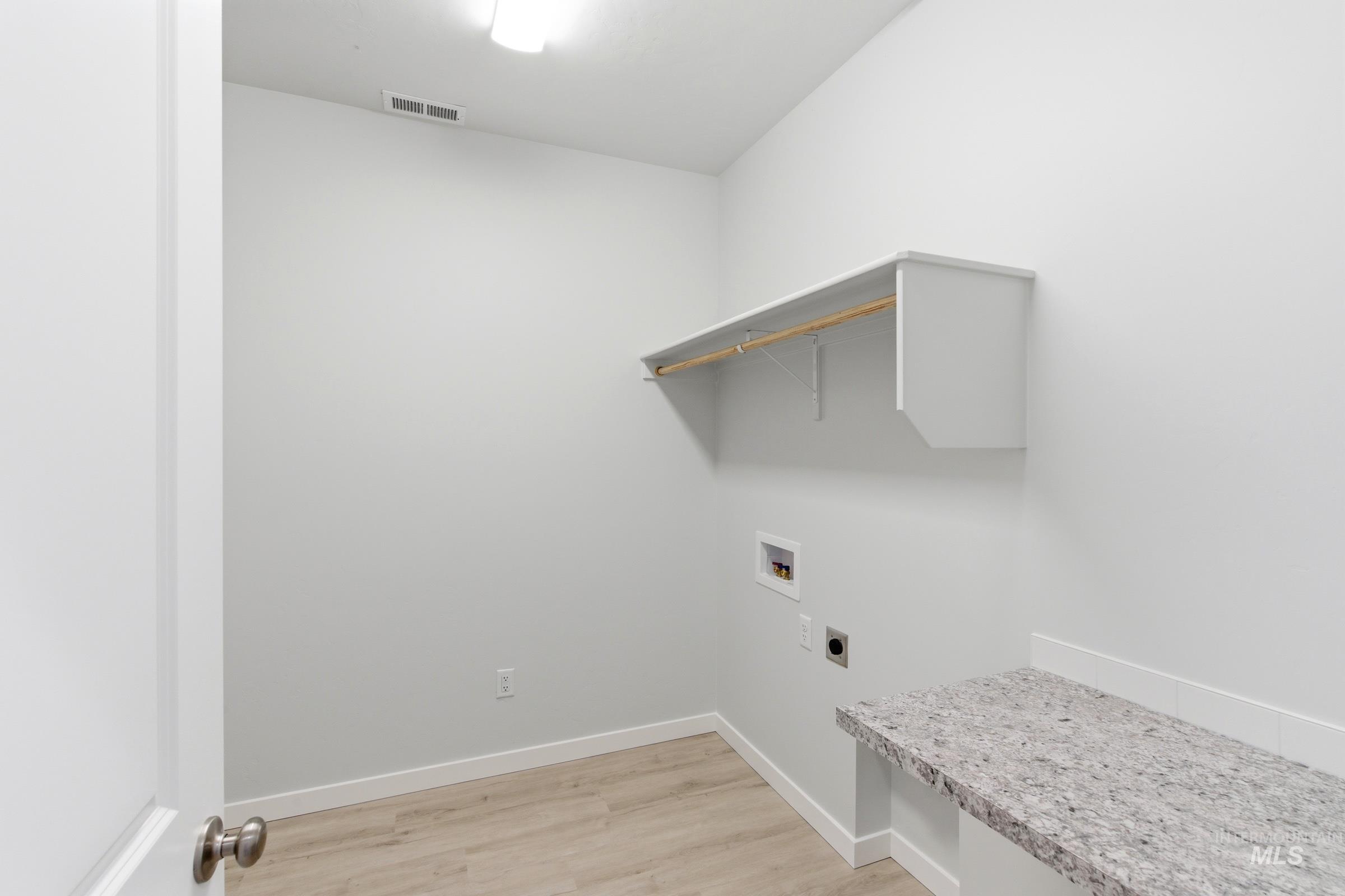 13663 Redway Court Caldwell, ID 83607 - Photo 25 of 32 Dedicated utility space featuring a built-in folding counter with a stone-finish surface, overhead shelving, and wood-finish flooring