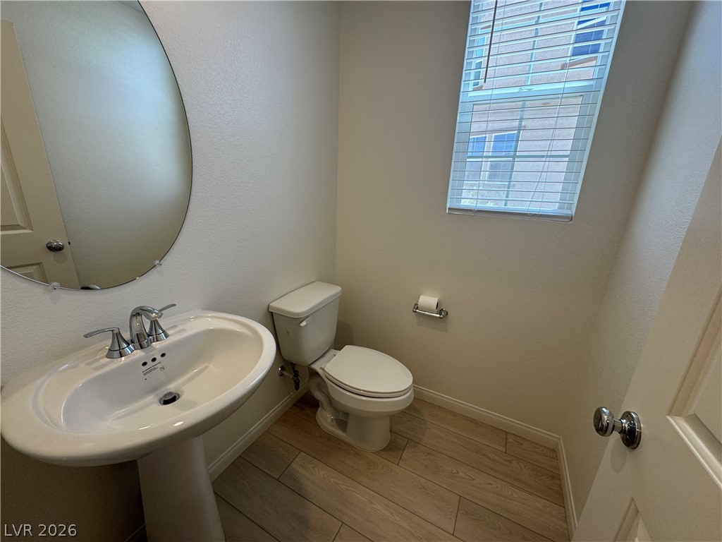 2821 Alcobaca Street Henderson, NV 89044 - Photo 8 of 24 A well-appointed half bath features a pedestal sink and contemporary wood-look flooring.