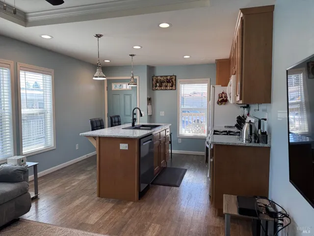 a kitchen with kitchen island granite countertop wooden floors and white cabinets
