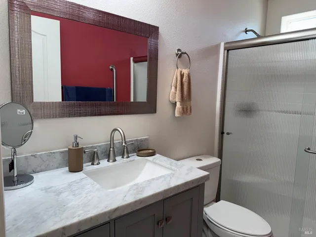 a bathroom with a granite countertop sink toilet and shower