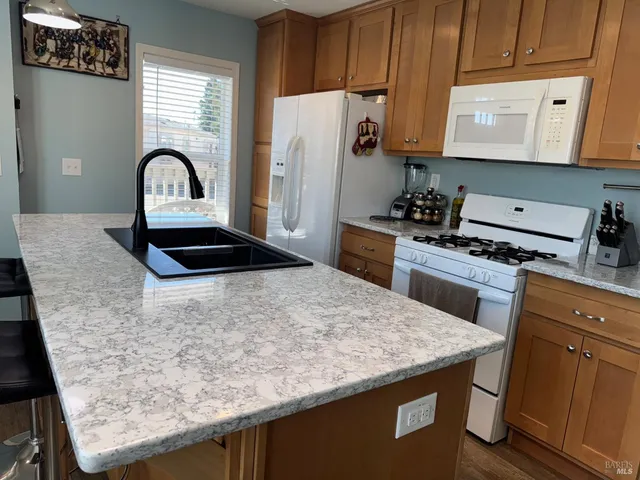 a kitchen with granite countertop a stove a sink and a refrigerator