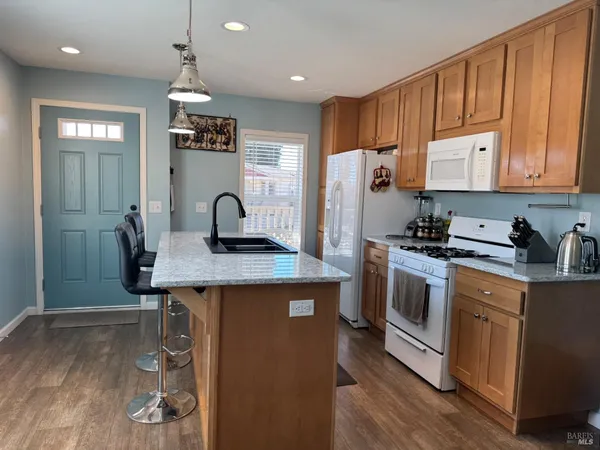a kitchen with kitchen island granite countertop wooden cabinets and refrigerator