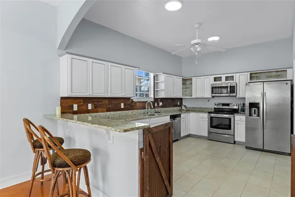 a kitchen with stainless steel appliances granite countertop a stove top oven a sink dishwasher and a refrigerator