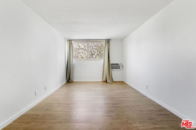 an empty room with wooden floor and window