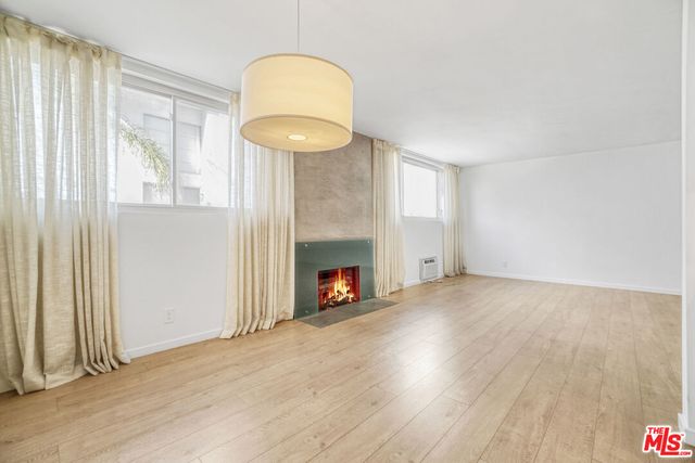 an empty room with wooden floor fireplace and windows
