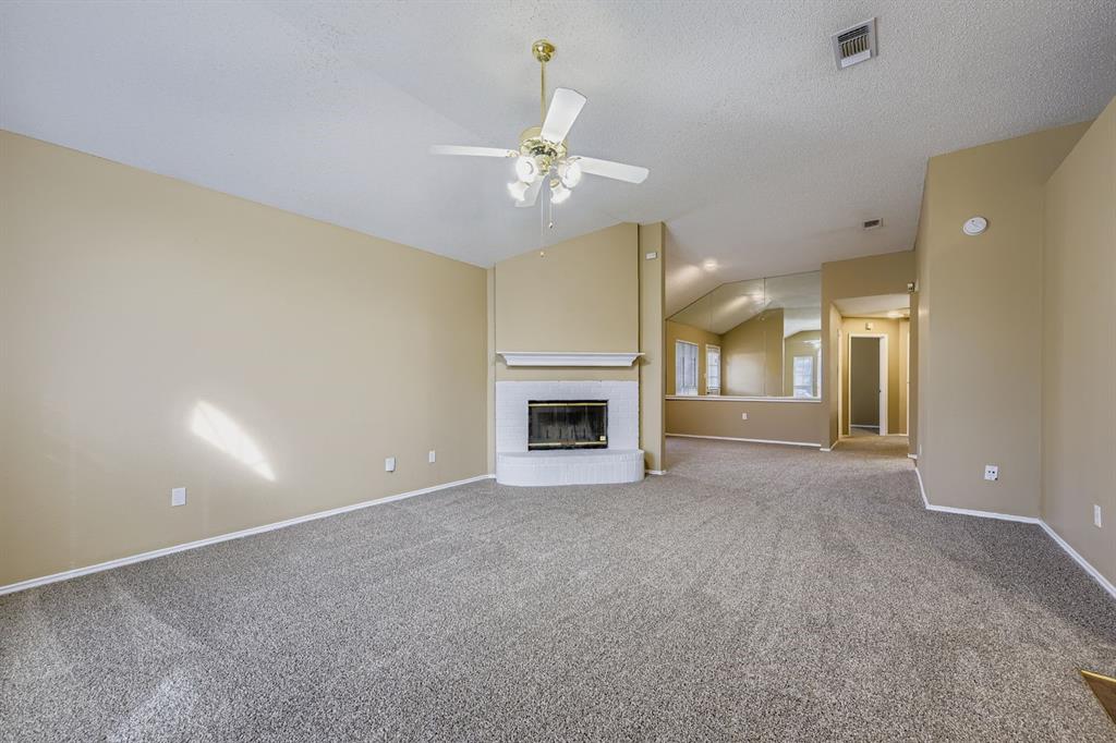 3326 Spring Meadow Lane Grand Prairie, TX 75052 - Photo 4 of 22 an empty room with a fireplace and fan
