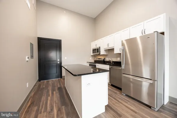 a kitchen with stainless steel appliances a refrigerator a sink and white cabinets
