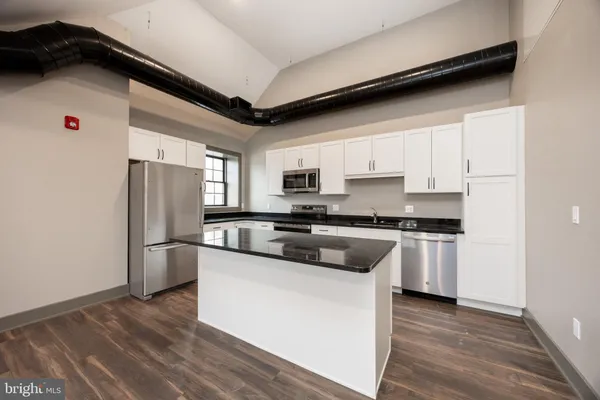 a kitchen with granite countertop a refrigerator and wooden floor