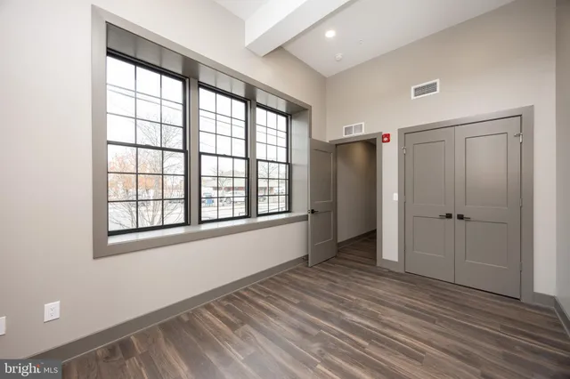 an empty room with wooden floor and windows