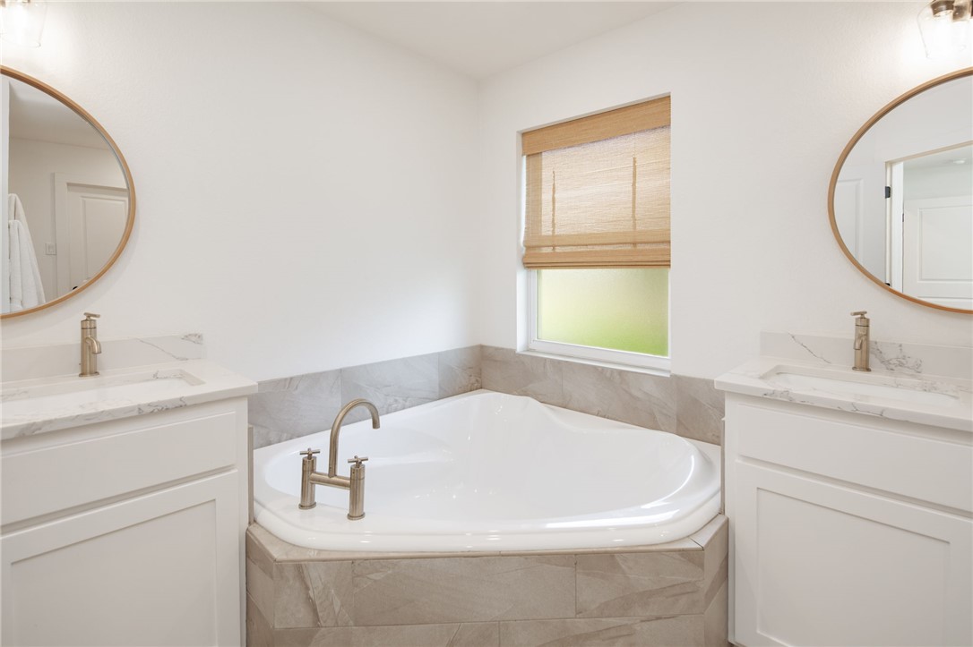 4700 Kensington Road Bryan, TX 77802 - Photo 17 of 31 Corner soaking tub with tile surround, flanked by two vanities