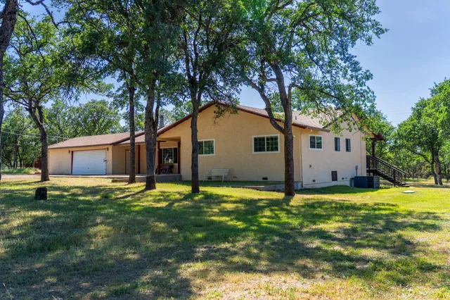 a backyard of house with large trees and wooden fence