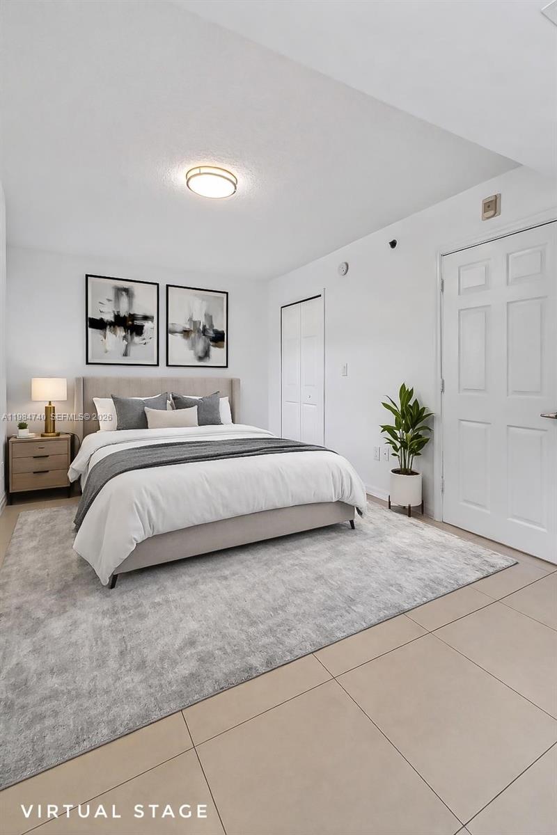 2475 Northwest 16th St Road, Unit 211 Miami, FL 33125 - Photo 22 of 29 a bedroom with a large bed and a painting on the wall