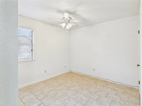 an empty room with a chandelier fan and windows